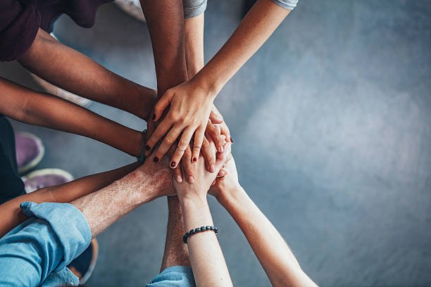 Equipa com mãos unidas em gesto de colaboração